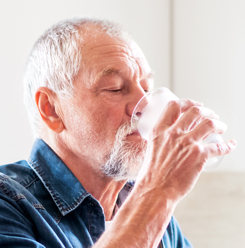 Älterer Mann trinkt sauberes klares Wasser aus einem Glas