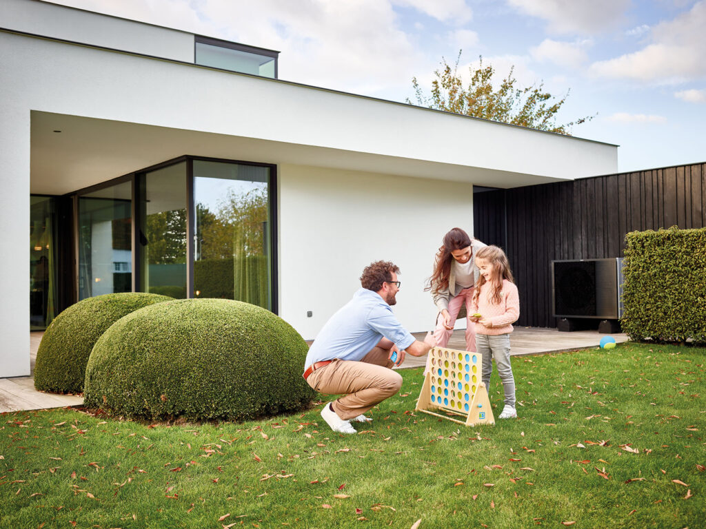 Familie Vater, Mutter, und Kinde spielen im Garten ein Holzspiel