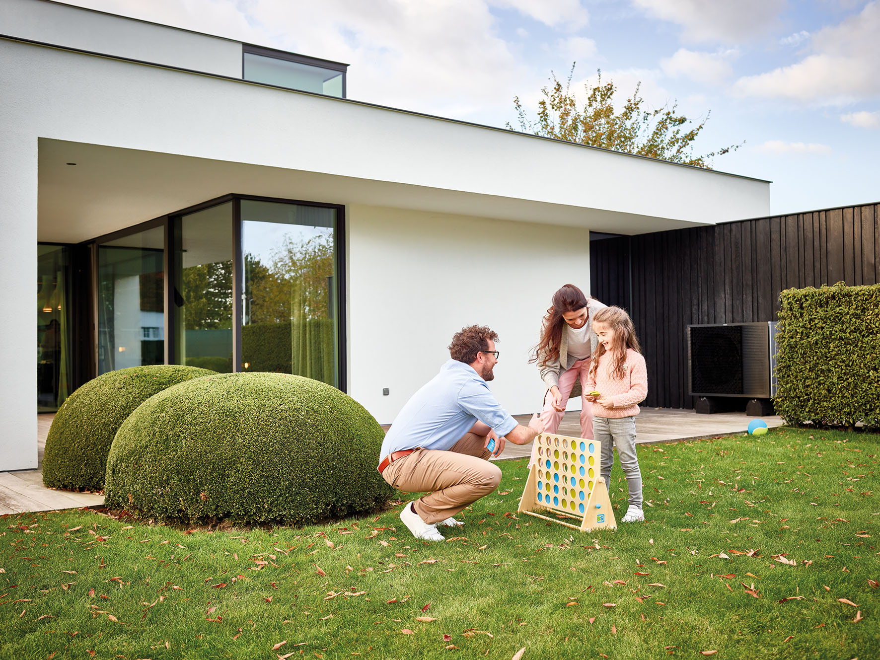 Familie Vater, Mutter, und Kinde spielen im Garten ein Holzspiel